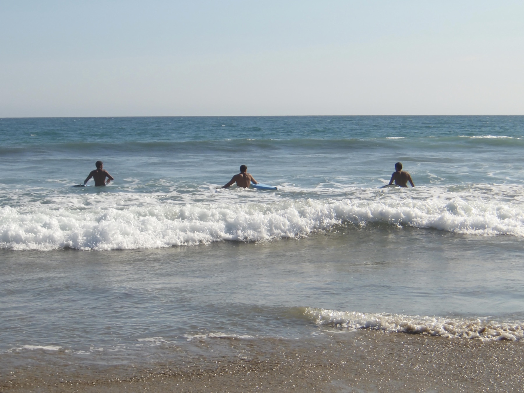 Three surfers waiting among the waves